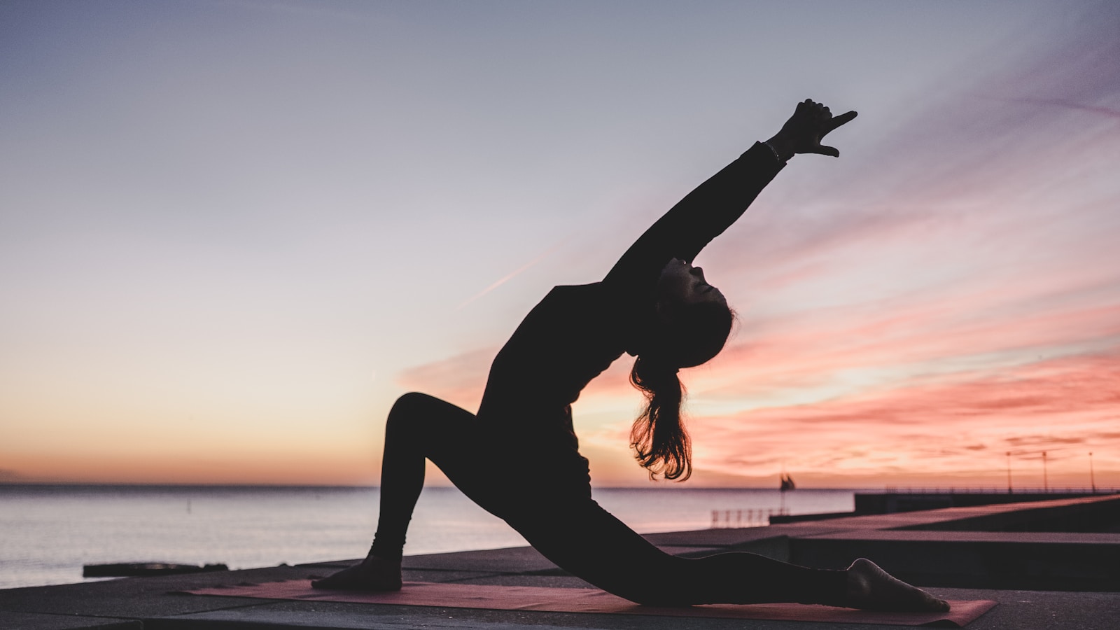 Person practising yoga in a sunlit room with a green mat