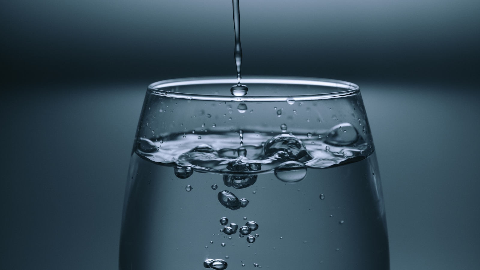 Glass of water beside a small plant on a wooden kitchen table