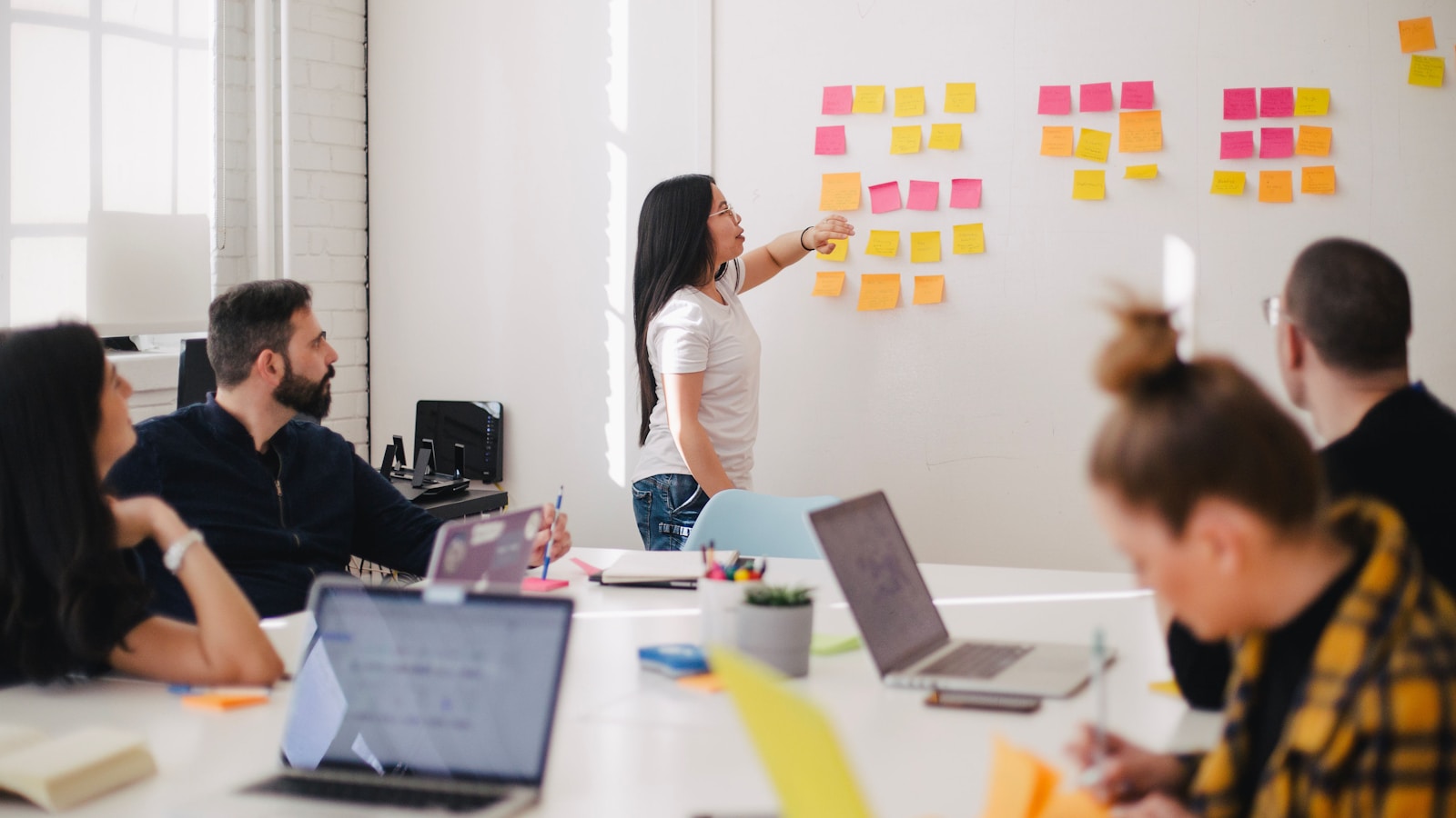 Group of colleagues collaborating around a whiteboard with sticky notes