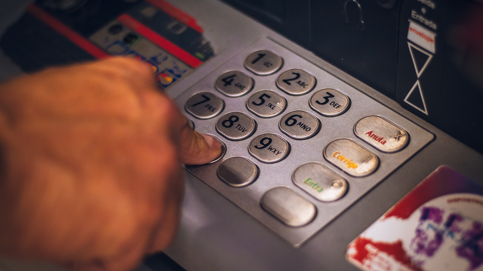 Hand placing coins in a stack with notebook of debt payoff plan