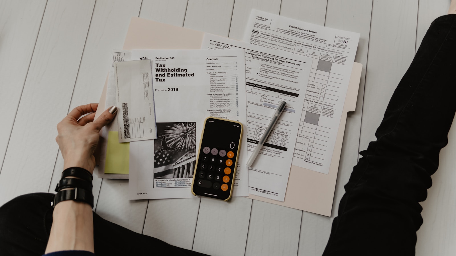 Person reviewing financial statements with a calculator and laptop