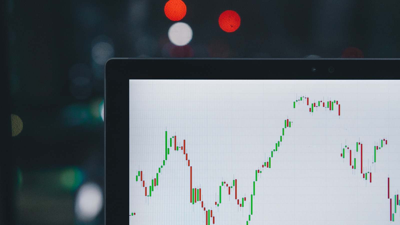 Stock chart on a smartphone next to a notebook and pen